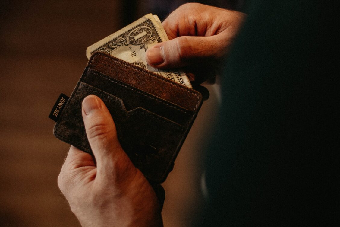 A person holding an open wallet with money in it.